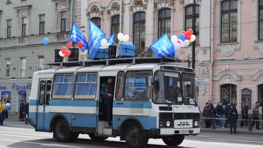 Olympische sporter zwaait vanuit een open bus tijdens een huldiging in een stad