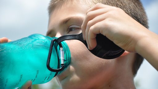 Persoon die water drinkt tijdens een wandeling op een warme zomerdag
