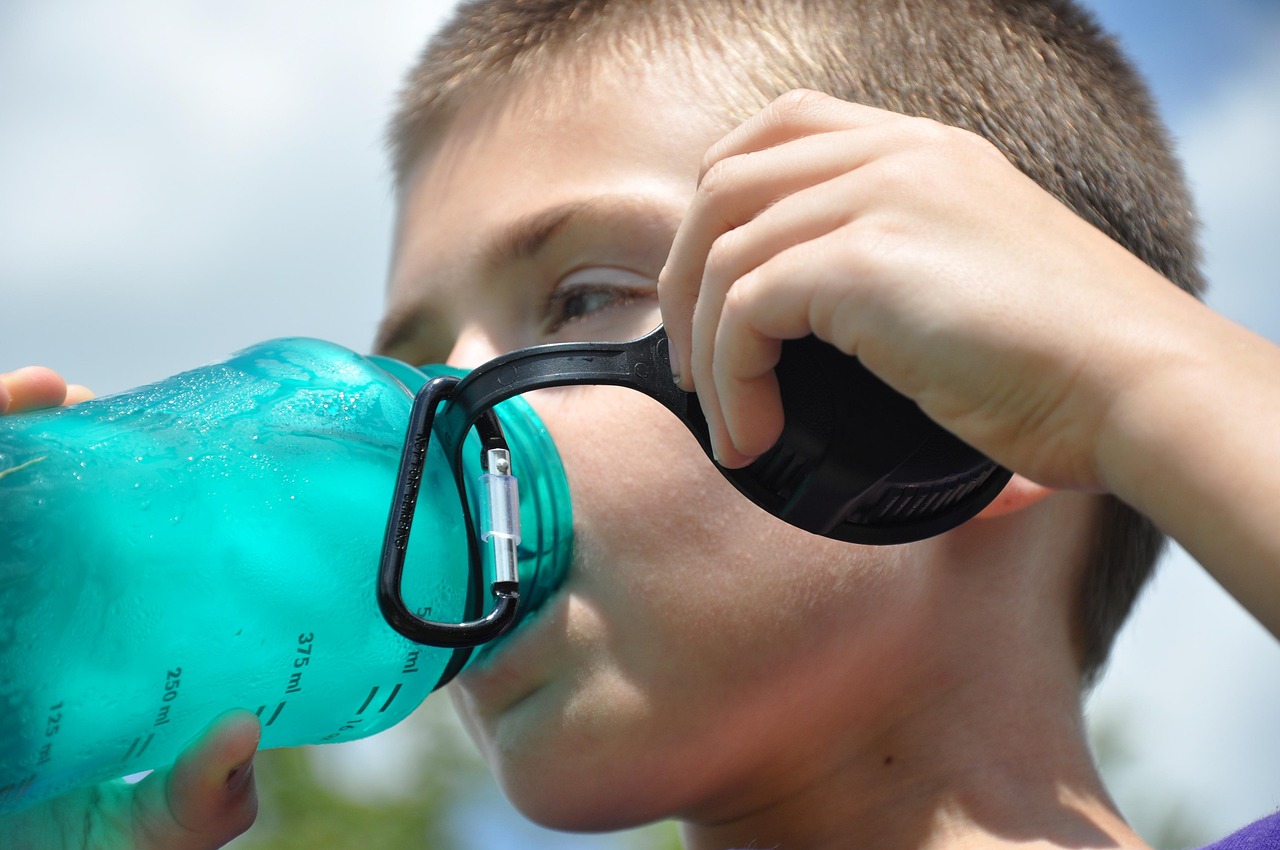 Persoon die water drinkt tijdens een wandeling op een warme zomerdag