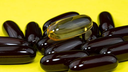 Ashwagandha wortel naast supplement capsules op een houten ondergrond