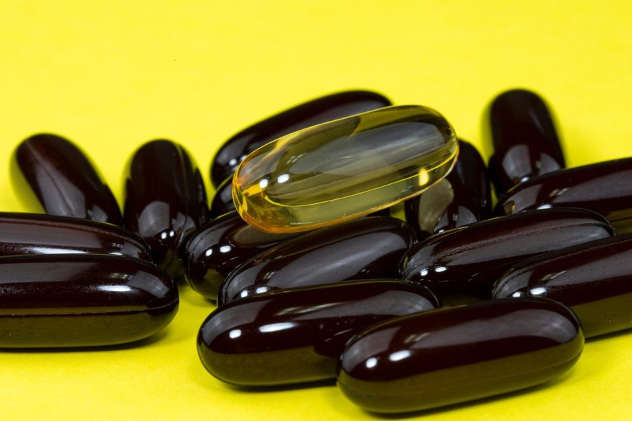Ashwagandha wortel naast supplement capsules op een houten ondergrond