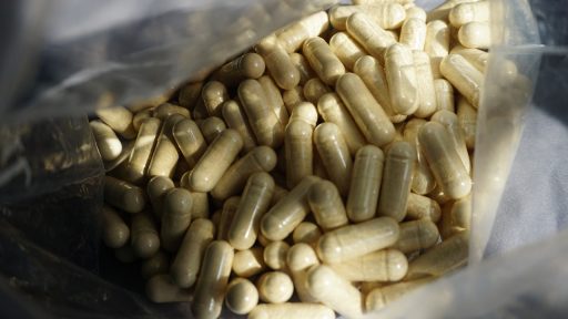 Potje met zinksupplementen en losse capsules op een houten ondergrond