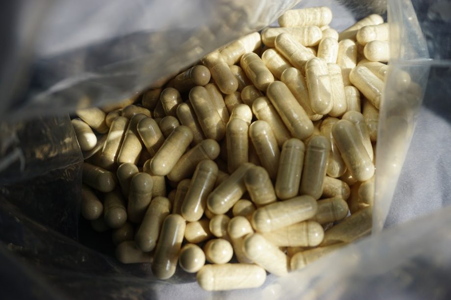 Potje met zinksupplementen en losse capsules op een houten ondergrond