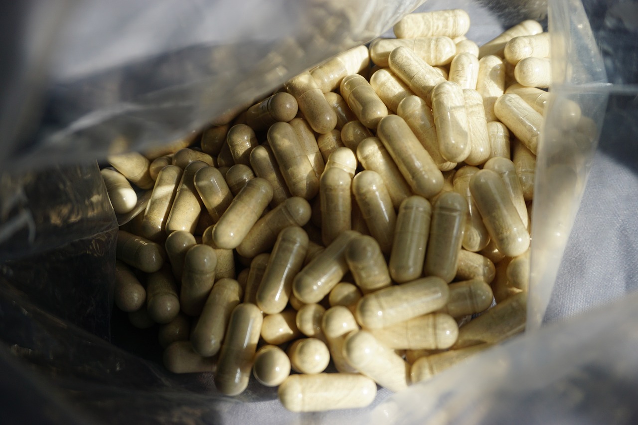 Potje met zinksupplementen en losse capsules op een houten ondergrond